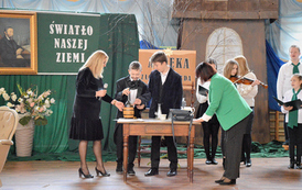 Akademia szkolna z okazji Dnia Patrona. Inscenizacja. Dzieci siedzą w ławkach. Odbywa się lekcja.  