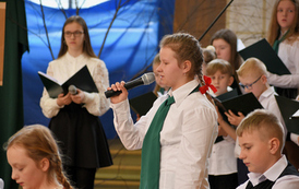 Akademia szkolna z okazji Dnia Patrona szkoły. Ch&oacute;r mieszany w biało-czarnych strojach. Dwoje uczni&oacute;w w strojach nawiązujących do czas&oacute;w kiedy żył Ignacy Łukasiewicz. 