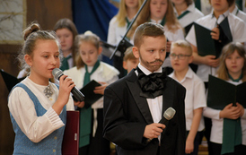 Akademia szkolna z okazji Dnia Patrona szkoły. Ch&oacute;r mieszany w biało-czarnych strojach. Dwoje uczni&oacute;w w strojach nawiązujących do czas&oacute;w kiedy żył Ignacy Łukasiewicz. 