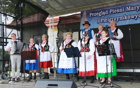 Zesp&oacute;ł Chorkowianie w tradycyjnych ludowych strojach. Zar&oacute;wno kobiety oraz mężczyźni. Występ na scenie podczas Gminnej Wigilii. 