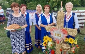 Grupa wieńcowa niosąca dożynkowy wieniec. 