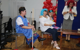 Kolorowo ubrane kobiety przedstawiające skecz na scenie. 