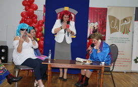 Kolorowo ubrane kobiety przedstawiające skecz na scenie. 