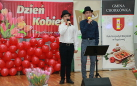 Dw&oacute;ch wokalist&oacute;w w białych koszulach i ciemnych kapeluszach. 