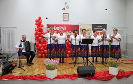 Na scenie kobiety w strojach ludowych. obok akordeonista. 