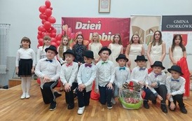 Zdjęcie grupowe dzieci, chłopcy w bialych koszulach i czarnych kapeluszach oraz dziewczynki w sukienkach. 