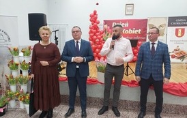 Cztery osoby osoby trzech elegancko ubranych mężczyzn oraz kobieta w sukience. Osoby przemawiają podczas dnia kobiet. 