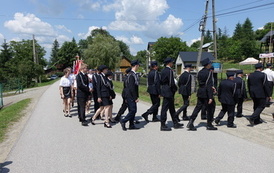 Zdjęcie wykonane podczas przemarszu uczestnik&oacute;w spotkania. Orkiestra Dęta na czele., tuz za nią strażacy w mundurach.