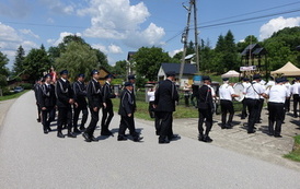Zdjęcie wykonane podczas przemarszu uczestnik&oacute;w spotkania. Orkiestra Dęta na czele., tuz za nią strażacy w mundurach. 