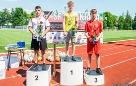 Podium i na nim nagrodzeni sportowcy. 