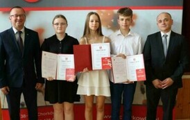 Na zdjęciu laureaci nagr&oacute;d w&oacute;jta gminy Chork&oacute;wka za osiągnięcie wysokich wynik&oacute;w w nauce. Uczniowie pozują na tle ścianki z herbem gminy w towarzystwie pana w&oacute;jta oraz dyrektor&oacute;w swoich szk&oacute;ł. 