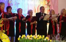Zesp&oacute;ł Nadzieja. Kobiety i mężczyźni w ciemnych strojach i czerwonych akcentach w postaci chusty. 