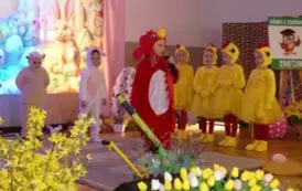 Grupa dzieci bierze udział w przedstawieniu scenicznym. Część dzieci ubrana jest w czerwone stroje kogut&oacute;w z ż&oacute;łtymi dziobami i czerwonymi grzebieniami, a druga część &ndash; w ż&oacute;łte stroje kurczak&oacute;w z czarnymi oczkami i puszystymi ogonkami. Jedno dziecko z gru