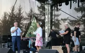 mezczyzna losuje z koszyka losy. Na scenie dwie kobiety, przedstawicielki kasy rolniczej