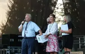 mezczyzna losuje z koszyka losy. Na scenie dwie kobiety, przedstawicielki kasy rolniczej. 