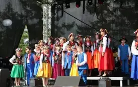 Dzieci zar&oacute;wno chłopcy jak i dziewczynki w strojach ludowych występują na scenie. 