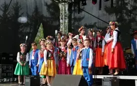 Dzieci zar&oacute;wno chłopcy jak i dziewczynki w strojach ludowych występują na scenie. 