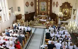 Poch&oacute;d dożynkowy. Korow&oacute;d wielu os&oacute;b ubranych elegancko, a także w stroje ludowe. Kobiety niosą dożynkowe wieńce. Niosą także chleby