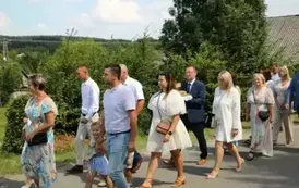 Poch&oacute;d dożynkowy. Korow&oacute;d wielu os&oacute;b ubranych elegancko, a także w stroje ludowe. Kobiety niosą dożynkowe wieńce. Niosą także chleby