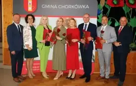 Nagrodzeni Dyrektorzy, pozują na tle ścianki z herbem gminy. 
