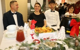 Troje elegancko ubranych os&oacute;b przy zastawionym potrawami stole. 