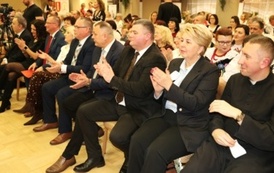 Ujęcie z boku na widownię. Wśr&oacute;d siedzących os&oacute;b widać dorosłych oraz dzieci.