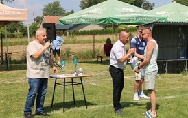 Seria dynamicznych i pozowanych zdjęć z amatorskiego turnieju piłki nożnej, kt&oacute;ry odbył się w pogodny, słoneczny dzień na trawiastym boisku otoczonym brzozami. Zdjęcia przedstawiają pełny przebieg wydarzenia sportowego. Galeria zawiera pozowane fotografie
