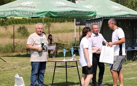 Seria dynamicznych i pozowanych zdjęć z amatorskiego turnieju piłki nożnej, kt&oacute;ry odbył się w pogodny, słoneczny dzień na trawiastym boisku otoczonym brzozami. Zdjęcia przedstawiają pełny przebieg wydarzenia sportowego. Galeria zawiera pozowane fotografie
