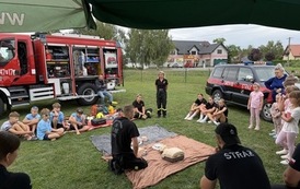 Seria fotografii dokumentujących plenerowe wydarzenie edukacyjne &bdquo;Akademia OLiOC&rdquo;, kt&oacute;re odbyło się na boisku trawiastym w Kopytowej pod patronatem Gminy Chork&oacute;wka. Zdjęcia przedstawiają praktyczne warsztaty z pierwszej pomocy przedmedycznej oraz prezenta
