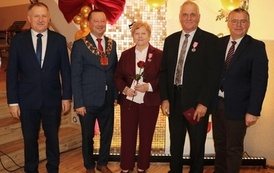 Zdjęcia z uroczystości Złotych God&oacute;w w Domu Ludowym w Zręcinie. Przedstawiają one występy męskiej sekcji Zespołu Śpiewaczego &bdquo;Chorkowianie&rdquo; w tradycyjnych strojach ludowych, oficjalne wystąpienie władz gminy Chork&oacute;wka oraz pamiątkowe kadry z jubilatami odznaczonymi Medalami za Długoletnie Pożycie Małżeńskie.