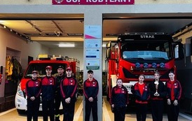 Zdjęcia przedstawiają uczestnik&oacute;w w strojach sportowych i strażackich podczas rywalizacji na hali sportowej, m.in. dynamiczne konkurencje z wężami strażackimi, uroczystą zbi&oacute;rkę wszystkich drużyn, a także momenty wręczania puchar&oacute;w, dyplom&oacute;w oraz nagr&oacute;d indywidualnych przez zaproszonych gości i przedstawicieli straży pożarnej.