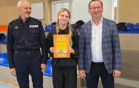 Zdjęcia przedstawiają uczestnik&oacute;w w strojach sportowych i strażackich podczas rywalizacji na hali sportowej, m.in. dynamiczne konkurencje z wężami strażackimi, uroczystą zbi&oacute;rkę wszystkich drużyn, a także momenty wręczania puchar&oacute;w, dyplom&oacute;w oraz nagr&oacute;d indywidualnych przez zaproszonych gości i przedstawicieli straży pożarnej.