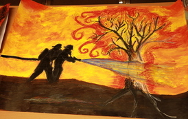 Praca plastyczna. Pomarańczowe tło a na nim podobizna strażak&oacute;w gaszących pożar. 