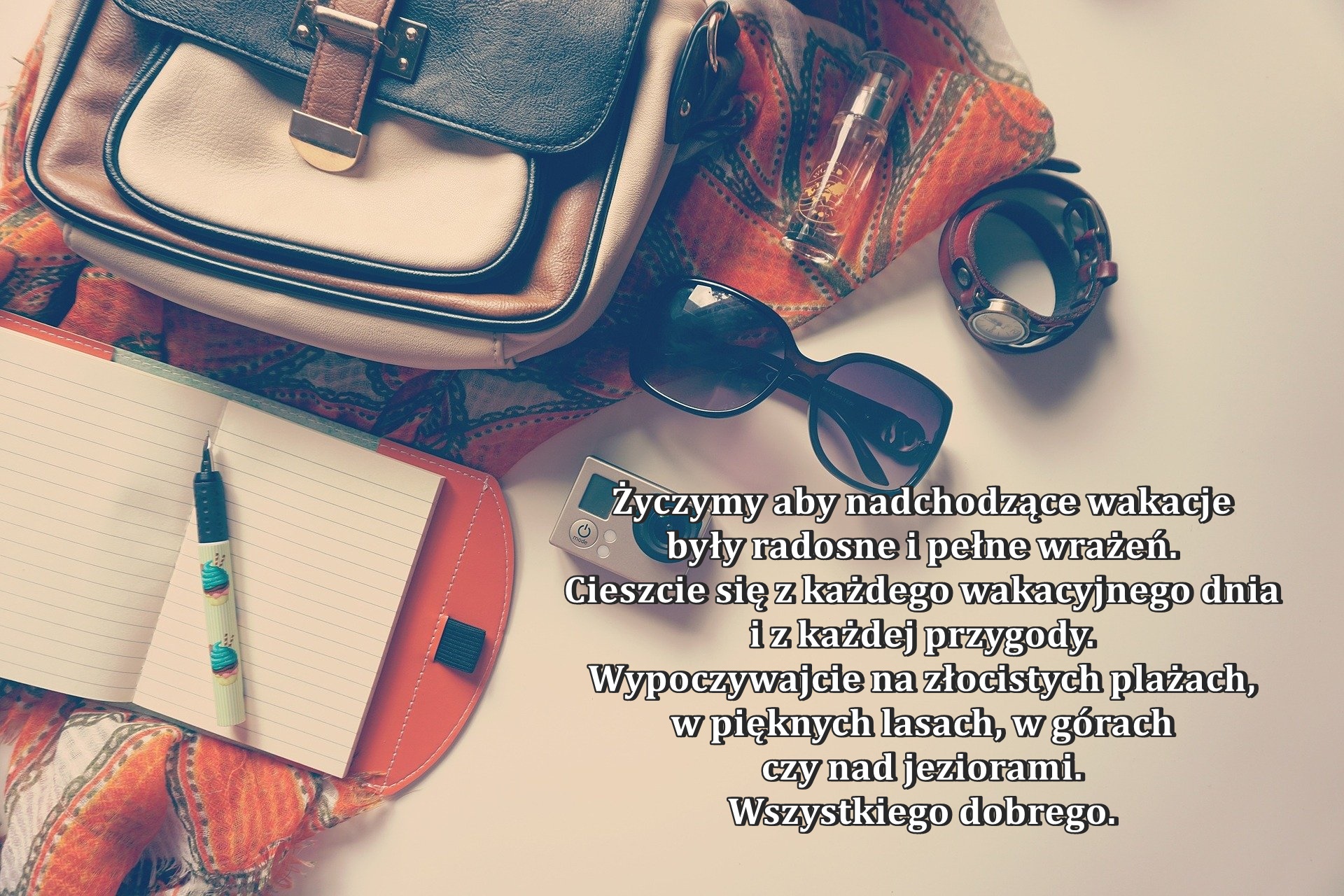 Życzenia na&nbsp;wakacje. Na zdjęciu torebka, notes, aparat, akcesoria kojarzone z&nbsp;wakacjami. 