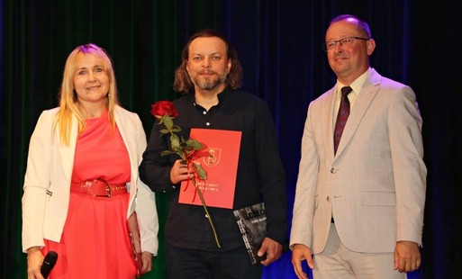 Paweł Malarczyk w towarzystwie wójta oraz pani dyrektor, stoi na scenie podczas wręczania nagrody. 