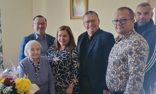 Grupowe zdjęcie przedstawicieli władzy z Jubilatką. 